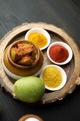 Homemade Mango Pickle or aam ka achar Kairi Loncha stored or preserved in China clay pot with...