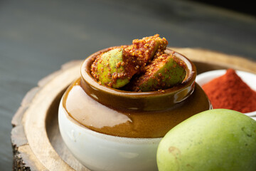 Homemade Mango Pickle or aam ka achar Kairi Loncha stored or preserved in China clay pot with...