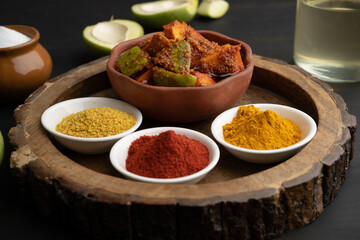 Homemade Mango Pickle or aam ka achar Kairi Loncha stored or preserved in China clay pot with Ingredients.