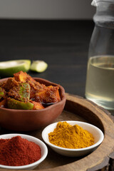 Homemade Mango Pickle or aam ka achar Kairi Loncha stored or preserved in China clay pot with Ingredients.