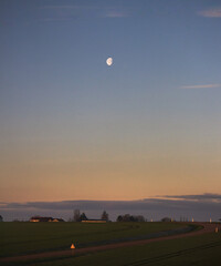A scenic landscape of a countryside with moonshine and green grass path and blue sky in the morning ambiance