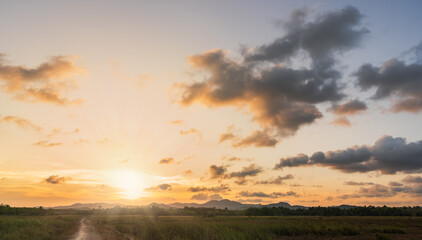 Sunset sky cloud in the evening over hill countryside with orange sunlight in golden hour, Horizon sky landscape nature backgrounds 