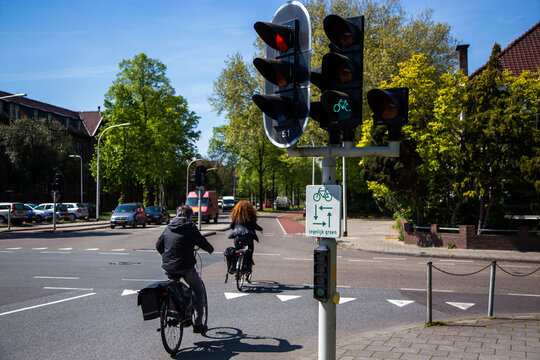 Two cyclists cross a priority road at a green traffic light for cyclists in the city of Deventer