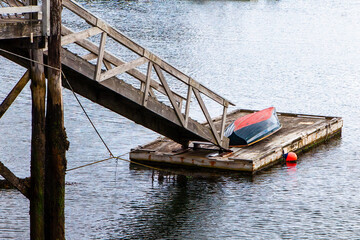 A floating dock in the water with boat and a red buoy next to it