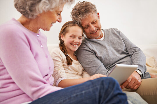 Tablet, grandma and grandpa with girl in house, senior and woman babysitting granddaughter. Living room, old man and female person with internet for growth and development of child with movies