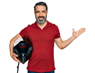 Middle aged man with beard holding motorcycle helmet celebrating victory with happy smile and winner expression with raised hands