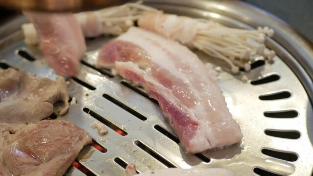 selective focus view to the pork meat while being grilled on the traditional korean charcoal pan stove called Galbi.
