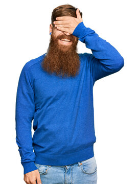 Young irish redhead man wearing casual clothes smiling and laughing with hand on face covering eyes for surprise. blind concept.