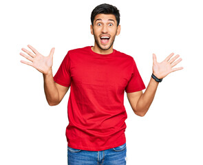 Naklejka premium Young handsome man wearing casual red tshirt celebrating crazy and amazed for success with arms raised and open eyes screaming excited. winner concept