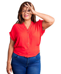 Fototapeta premium Middle age latin woman wearing casual clothes smiling happy doing ok sign with hand on eye looking through fingers