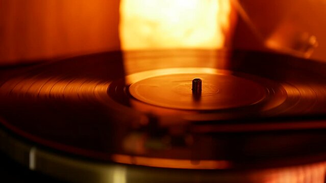 Rotating vinyl record on a retro turntable in the light of a warm orange lamp