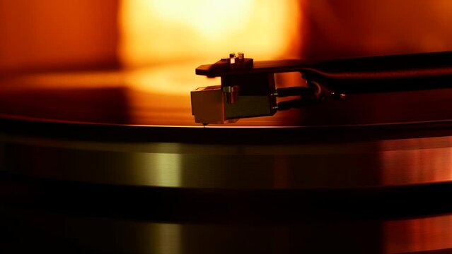 Headshell with the needle of the record player slowly lowers onto the vinyl record.