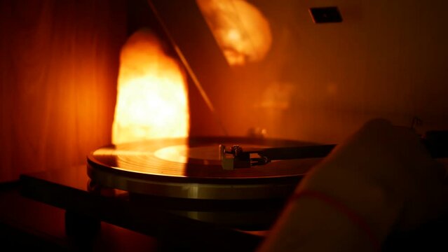 Male hands place a vinyl record on the turntable. The needle slowly drops onto the vinyl record.