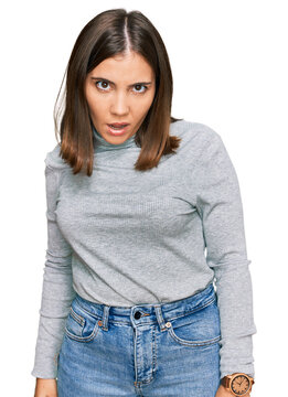 Young beautiful woman wearing casual turtleneck sweater in shock face, looking skeptical and sarcastic, surprised with open mouth