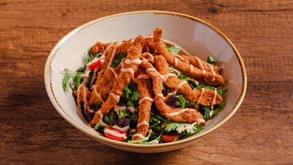 Fried chicken and vegetables salad bowl on wooden background