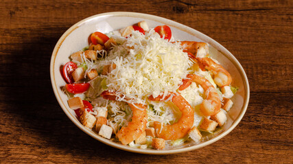 Shrimps caesar salad bowl on wooden background