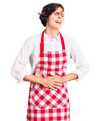Beautiful young woman with short hair wearing professional cook apron with hand on stomach because...