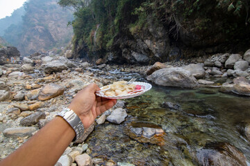 A male traveler enjoying Momo on the bank of a mountain river.