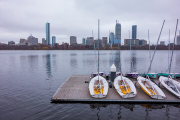 Docked boats on the Charles River with the Boston Skyline behind on an overcast day.