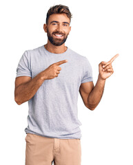 Young hispanic man wearing casual clothes smiling and looking at the camera pointing with two hands...