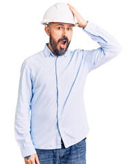 Young handsome man wearing architect hardhat surprised with hand on head for mistake, remember...
