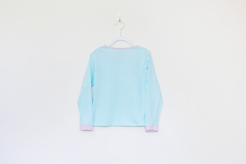 Girl's turquoise blue long sleeve T-shirt top with pink cuffs and neckline hung against cream background 