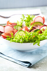 Healthy Salad with Tomatoes, Radish and Lettuce. Easy summer snack. Bright wooden background. Copy space.	
