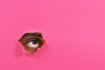 Tear, hole and eye of person on pink background for vision, eyesight and looking for inspiration....
