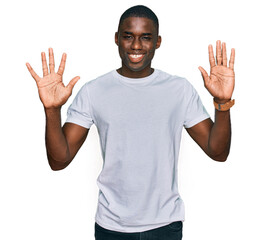 Young african american man wearing casual white t shirt showing and pointing up with fingers number ten while smiling confident and happy.