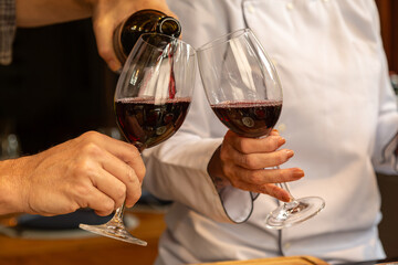 detalhe das mão de Sommelier servindo vinho tinto para degustação elegante. - obrazy, fototapety, plakaty