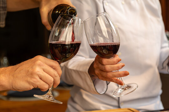 detalhe das m&atilde;o de Sommelier servindo vinho tinto para degusta&ccedil;&atilde;o elegante.