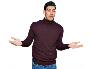 Handsome hispanic man wearing casual turtleneck sweater clueless and confused expression with arms and hands raised. doubt concept.