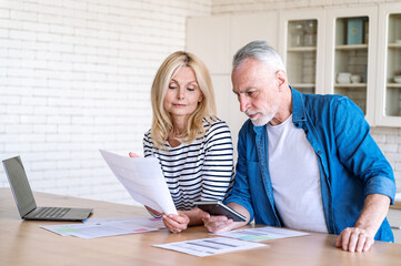 Worried middle aged man and woman paying utility bill online
