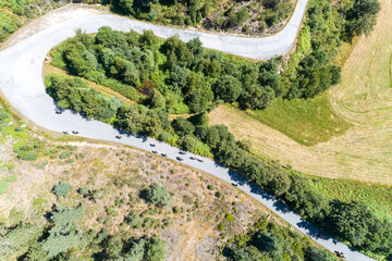 drone aerial top view of riders on a curvy mountain road in the summertime