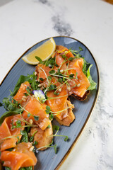 top view Smoked salmon with lemon and microgreens on a blue plate