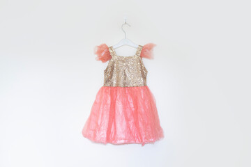 girls sparkly gold and peach sequin party dress on hanger against cream background 