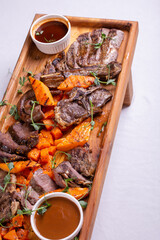 wooden board of assorted meats, pumpkin, and sauces.