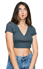 Young beautiful teen girl wearing casual crop top t shirt making fish face with lips, crazy and comical gesture. funny expression.