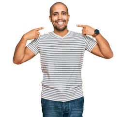 Hispanic adult man wearing casual clothes smiling cheerful showing and pointing with fingers teeth and mouth. dental health concept.
