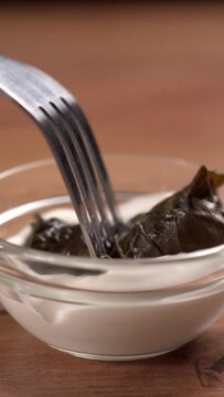 Dolma, stuffed grape leaves dipped in sour cream