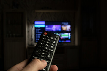 A person switches channels on a TV using a remote control. In the hand of a person, a TV remote...