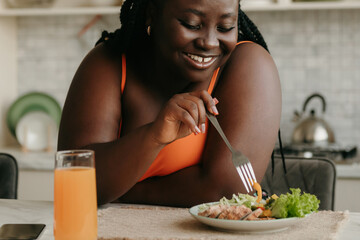 Beautiful curvy African woman enjoying healthy eating for lunch at home