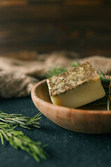 Solid shampoo with rosemary in a wooden plate on a dark background