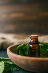 Bottle of essential oil with mint on wooden background