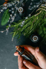 Essential oil in hands close-up with natural herbs