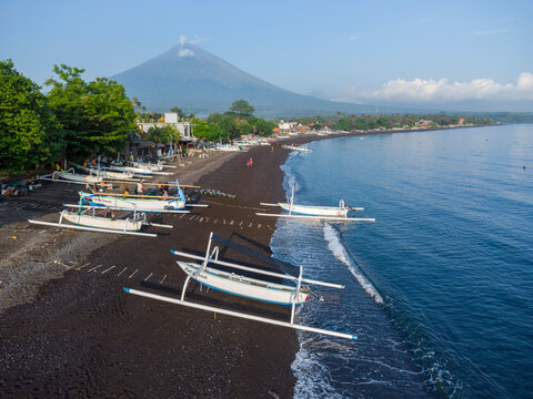 Fischer laden am Morgen, am schwarzen Strand von Amed, Fische aus ihren Auslegerboote, Berg Agung im Hintergrund, Amed Bali, Indonesien