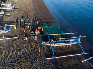 Fischer laden am Morgen, am schwarzen Strand von Amed, Fische aus ihren Auslegerboote, Berg Agung im Hintergrund, Amed Bali, Indonesien - obrazy, fototapety, plakaty