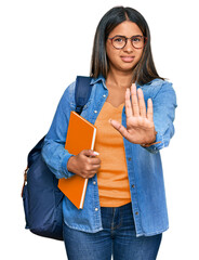 Young latin girl wearing student backpack and holding books doing stop gesture with hands palms, angry and frustration expression