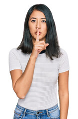 Beautiful asian young woman wearing casual white t shirt asking to be quiet with finger on lips. silence and secret concept.