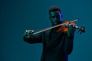 Elegant African American Man in Suit Playing Violin on Vibrant Blue Background for Creative Musical...